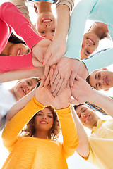 Image showing smiling teenagers with hands on top of each other