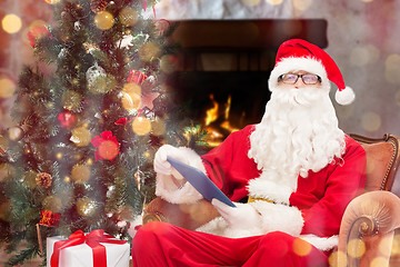 Image showing santa claus with tablet pc in armchair at home