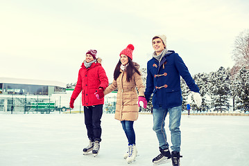 Image showing happy friends ice skating on rink outdoors