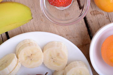 Image showing healthy strawberry and bananas slices on wooden background