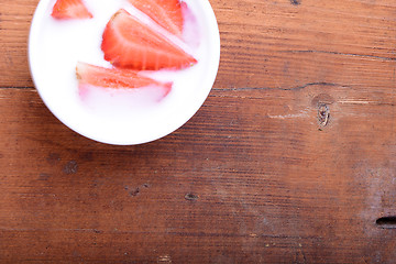 Image showing Slice of pie with strawberry on white plate, milk drink, wooden background. Top view