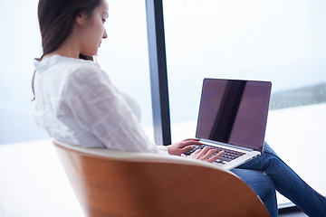 Image showing relaxed young woman at home working on laptop computer