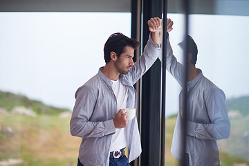 Image showing relaxed young man drink first morning coffee withh rain drops on