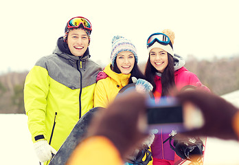 Image showing happy friends with snowboards and smartphone