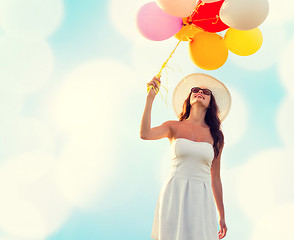 Image showing smiling young woman in sunglasses with balloons