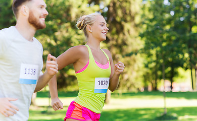 Image showing happy sportsmen couple racing wit badge numbers