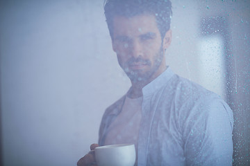 Image showing relaxed young man drink first morning coffee withh rain drops on