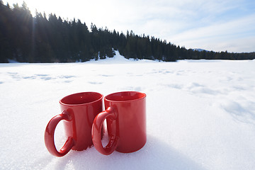 Image showing two red coups of hot tea drink in snow  at winter