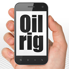 Image showing Manufacuring concept: Hand Holding Smartphone with Oil Rig on display