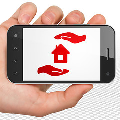 Image showing Insurance concept: Hand Holding Smartphone with House And Palm on display