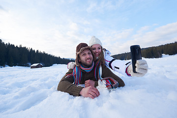 Image showing romantic couple have fun in fresh snow and taking selfie