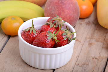 Image showing Bananas apple mandarin peach strawberry on wooden background as health food concept