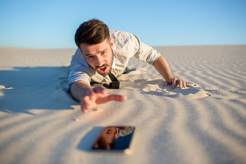 Image showing Poor signal. businessman searching for mobile phone signal in desert