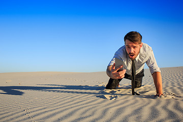 Image showing Poor signal. businessman searching for mobile phone signal in desert