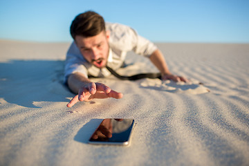 Image showing Poor signal. businessman searching for mobile phone signal in desert