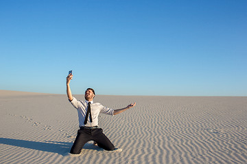 Image showing Poor signal. businessman searching for mobile phone signal in desert