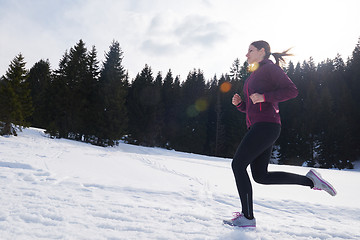 Image showing yougn woman jogging outdoor on snow in forest