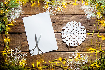 Image showing The blank sheet of paper on the wooden table with a scissors 