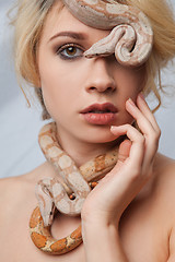 Image showing Beautiful girl and the snake Boa constrictors, which wraps around her face