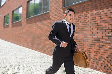 Image showing Chinese young businessman running in a city street