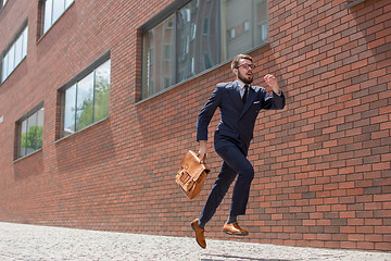 Image showing young businessman running in a city street