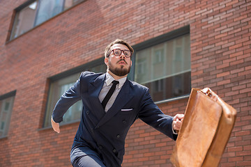 Image showing young businessman running in a city street