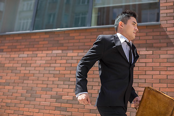 Image showing Chinese young businessman running in a city street