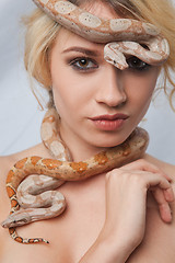 Image showing Beautiful girl and the snake Boa constrictors, which wraps around her face