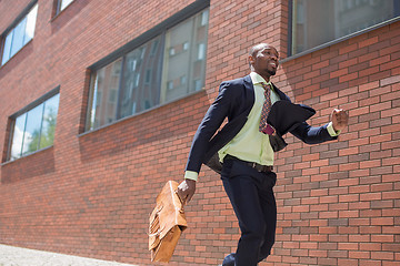 Image showing african black young businessman running in a city street