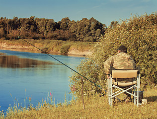 Image showing Fisherman with a fishing rod on the river Bank.