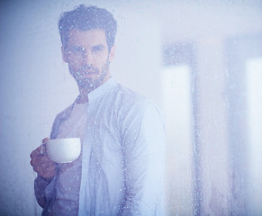 Image showing relaxed young man drink first morning coffee withh rain drops on