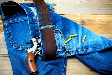 Image showing revolver nagant with cartridges in old blue jeans