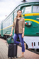 Image showing smiling middle-aged woman with luggage near old train