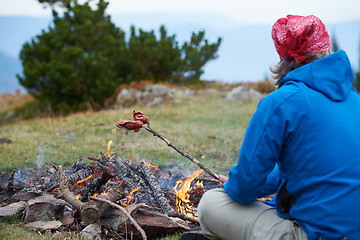 Image showing hiking man prepare tasty sausages on campfire