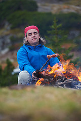 Image showing hiking man prepare tasty sausages on campfire