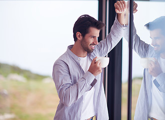 Image showing relaxed young man drink first morning coffee withh rain drops on