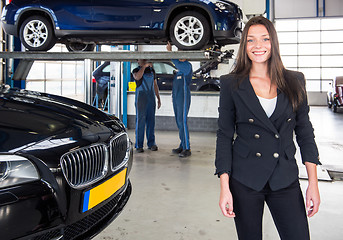 Image showing Satisfied customer standing in front of her car at a garage