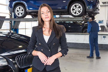 Image showing Pleased customer standing in front of her fixed car