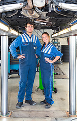 Image showing Two car mechanics underneath a vehicle on a hydraulic  car lift