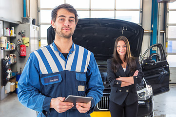 Image showing Proud mechanic, posing in front of a client with her car