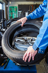 Image showing Mechanic putting a tire on a light weight alloy rim