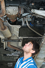 Image showing Mechanic examining the exhaust of a car