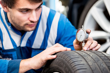 Image showing Mechanic, checking the wear on the tread of a tire