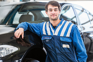 Image showing Professional mechanic leaning against a car