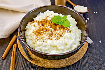 Image showing Rice porridge with cinnamon in bowl on dark board