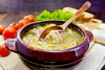 Image showing Soup with meatballs and spoon in pottery on board