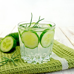 Image showing Lemonade with cucumber and rosemary in glassful on napkin and bo