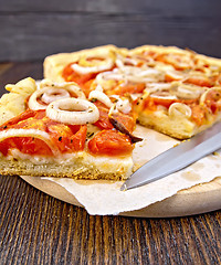Image showing Pie with onions and tomatoes on paper with knife