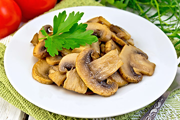 Image showing Champignons fried in plate and tomatoes on light board