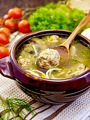 Image showing Soup with meatballs and spoon in pottery on napkin